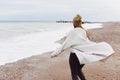 A beautiful young girl walks along the seashore, a storm, hair fly apart, a gray cardigan, a sports figure in sneakers Royalty Free Stock Photo