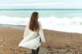 A beautiful young girl walks along the seashore, a storm, hair fly apart, a gray cardigan, a sports figure in sneakers Royalty Free Stock Photo