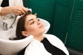 Beautiful young girl washes her head in a beauty studio. Hairdresser is washing hair for client Royalty Free Stock Photo