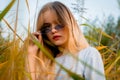 Beautiful young girl posing against high grass