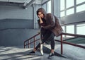 A beautiful young girl wearing a checkered shirt and coat with her skateboard sitting on a grind rail in skatepark Royalty Free Stock Photo