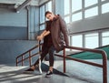 A beautiful young girl wearing a checkered shirt and coat with her skateboard sitting on a grind rail in skatepark Royalty Free Stock Photo