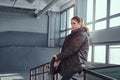 A beautiful young girl wearing a checkered shirt and coat with her skateboard sitting on a grind rail in skatepark Royalty Free Stock Photo