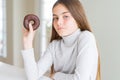 Beautiful young girl wearing eating a chocolate donut with a confident expression on smart face thinking serious