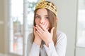 Beautiful young girl wearing a golden crown as a princess from fairytale shocked covering mouth with hands for mistake Royalty Free Stock Photo