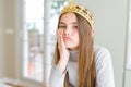 Beautiful young girl wearing a golden crown as a princess from fairytale thinking looking tired and bored with depression problems