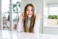 Beautiful young girl wearing headphones listening to music and dancing pointing and showing with thumb up to the side with happy Royalty Free Stock Photo