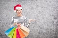 Beautiful young girl wearing a Santa hat holding lots of shopping bags Royalty Free Stock Photo