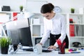 A young girl in the office is standing near the table, holding a pencil and a calculator in her hand and looking through Royalty Free Stock Photo