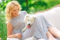 Beautiful young girl with a white puppy in her arms on a retro sofa in a summer garden Royalty Free Stock Photo