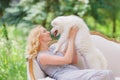 Beautiful young girl with a white puppy in her arms on a retro sofa in a summer garden Royalty Free Stock Photo