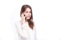 Beautiful young girl in a white shirt on white isolated background talking on a mobile phone. Smiles portrait to the Royalty Free Stock Photo