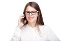 Beautiful young girl in a white shirt on white isolated background talking on a mobile phone. Smiles portrait to the Royalty Free Stock Photo