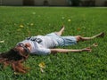 A beautiful young girl in a white T shirt with inscription Break a tree and skirt lies on the grass