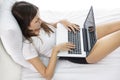 Beautiful young girl working on her laptop while lying on bed Royalty Free Stock Photo