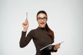 Beautiful young girl writing in notebook and got an idea. Looking at camera. Over white background Royalty Free Stock Photo