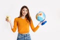 A beautiful young girl in a yellow sweater is holding a globe and a camera. Recreation, travel, tourism Royalty Free Stock Photo