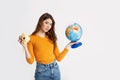 A beautiful young girl in a yellow sweater is holding a globe and a camera. Recreation, travel, tourism Royalty Free Stock Photo