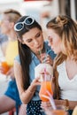 beautiful young girlfriends drinking summer cocktail together