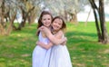 Beautiful young girls with blue eyes in a white dresses in the garden with apple trees blosoming having fun and enjoying smell of Royalty Free Stock Photo