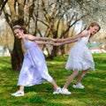 Beautiful young girls with blue eyes in a white dresses in the garden with apple trees blosoming having fun and enjoying smell of Royalty Free Stock Photo