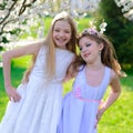 Beautiful young girls with blue eyes in a white dresses in the garden with apple trees blosoming having fun and enjoying smell of Royalty Free Stock Photo