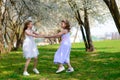 Young girls with blue eyes in white dresses in garden with apple trees blosoming