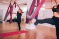 Beautiful young girls doing fly yoga on hammocks, stretching legs, taking care of health