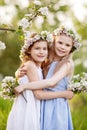 Beautiful young girls in long dresses in the garden with blosoming  apple trees. Smiling girls embracing, having fun and enjoying Royalty Free Stock Photo