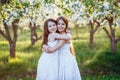 Beautiful young girls in white dresses in the garden with apple trees blosoming at the sunset. two friends hugging Royalty Free Stock Photo