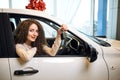 Beautiful young gorgeous woman is getting key and smiling while sitting in a new car Royalty Free Stock Photo
