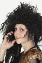 Beautiful young Goth woman with teased hair using mobile phone Royalty Free Stock Photo