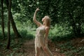 Beautiful young graceful blonde woman dancing. In the woods in summer.