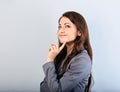 Beautiful young happy business woman with finger under the face thinking and looking up in grey suit and long hair. Closeup Royalty Free Stock Photo