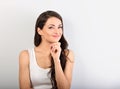 Beautiful young happy casual woman with finger under the face thinking and looking up in white shirt and long hair Royalty Free Stock Photo