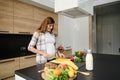 Beautiful pregnant woman chopping yellow bell pepper on a cutting board, preparing healthy meal in the kitchen island Royalty Free Stock Photo