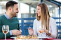 Beautiful young happy couple enjoying lunch and wine in outdoor restaurant