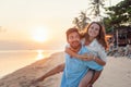 Beautiful young happy couple in love having fun on the beach at sunset during the honeymoon vacation travel, the guy carries the Royalty Free Stock Photo