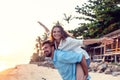 Beautiful young happy couple in love having fun on the beach at sunset during the honeymoon vacation travel, the guy carries the Royalty Free Stock Photo