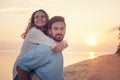 Beautiful young happy couple in love having fun on the beach at sunset during the honeymoon vacation travel, the guy carries the Royalty Free Stock Photo