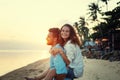 Beautiful young happy couple in love having fun on the beach at sunset during the honeymoon vacation travel, the guy carries the Royalty Free Stock Photo