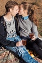 Beautiful young happy couple in love sitting on lake shore on a warm Sunny evening kissing and drinking warm tea Royalty Free Stock Photo