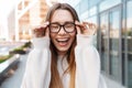 Beautiful young happy excited business woman posing walking outdoors near business center wearing eyeglasses Royalty Free Stock Photo