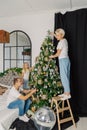 Beautiful young happy family decorate the christmas tree.