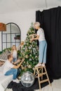 Beautiful young happy family decorate the christmas tree.