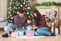 Beautiful young happy family caucasian mother father and child in plaid shirt and jeans sitting near christmas tree and fireplace Royalty Free Stock Photo