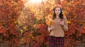 Beautiful young happy girl with a bright red-yellow autumn leaf and cup of coffee in the park Royalty Free Stock Photo