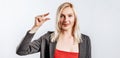 Beautiful young happy girl showing small size gesture on gray isolated background Royalty Free Stock Photo