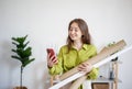 Beautiful young happy woman architect designer with smartphone holding blueprints. Architect are planning new project Royalty Free Stock Photo