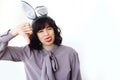 Beautiful young happy woman in bunny ears showing thumb down and smiling on white background indoors, space for text. Disapprove Royalty Free Stock Photo